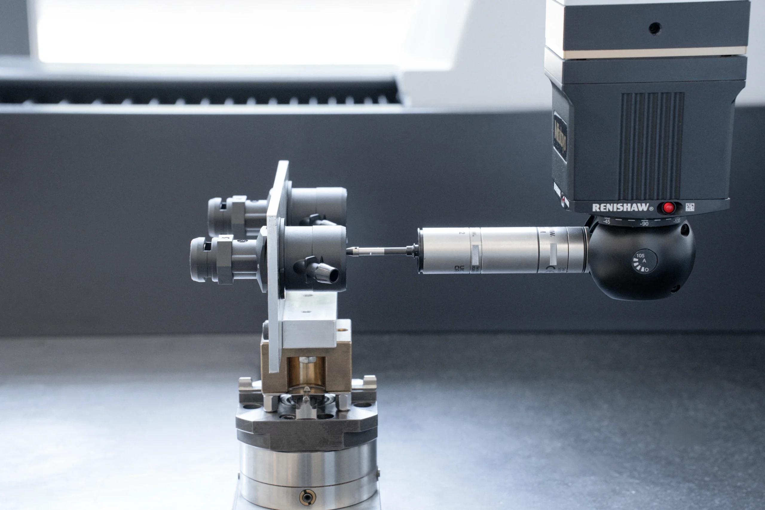 Sonda a contatto Renishaw di una macchina di misura mentre controlla un pezzo metallico bloccato su un attrezzo di staffaggio.